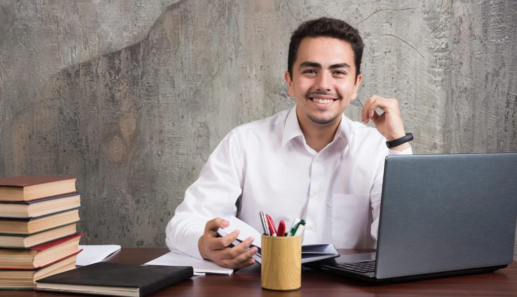 Technology professional working at a desk with a laptop and notebook